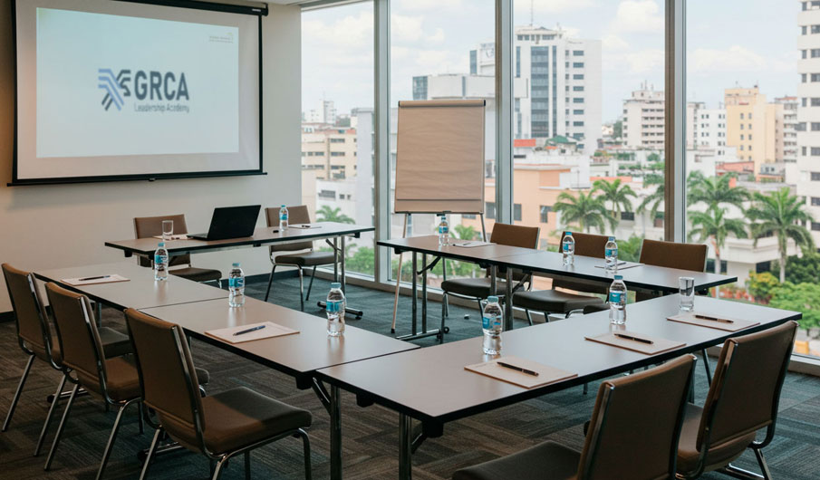 Sala de reuniones moderna con vista panorámica a la ciudad, mesas en disposición de trabajo colaborativo y proyector encendido.